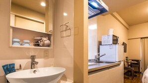 A compact kitchen with a white sink, a microwave, and a small dining area with a chair and table. - Mr. Kinjo Link in Kume Naha (Naha)
