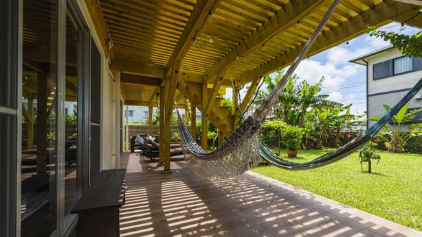 A covered outdoor area with a hammock, wooden flooring, and a bench. - Panorama (Yomitan)