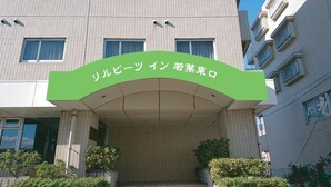 Un bâtiment avec une enseigne verte sur laquelle on peut lire « Sakura Hotel ».