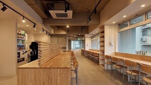 Un café moderne doté d’un long comptoir en bois et de plusieurs espaces où s’asseoir.