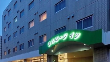 A multi-story hotel with a green sign above the entrance.