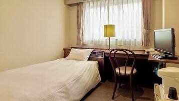 Habitación de hotel con dos camas individuales, un escritorio con silla, televisor y ventana con cortinas.