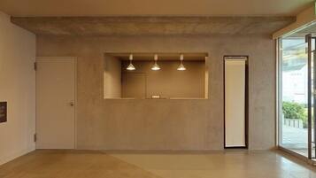 Un interno moderno con un design minimalista, che include una reception con illuminazione a sospensione, un grande specchio e una porta che dà su un balcone.