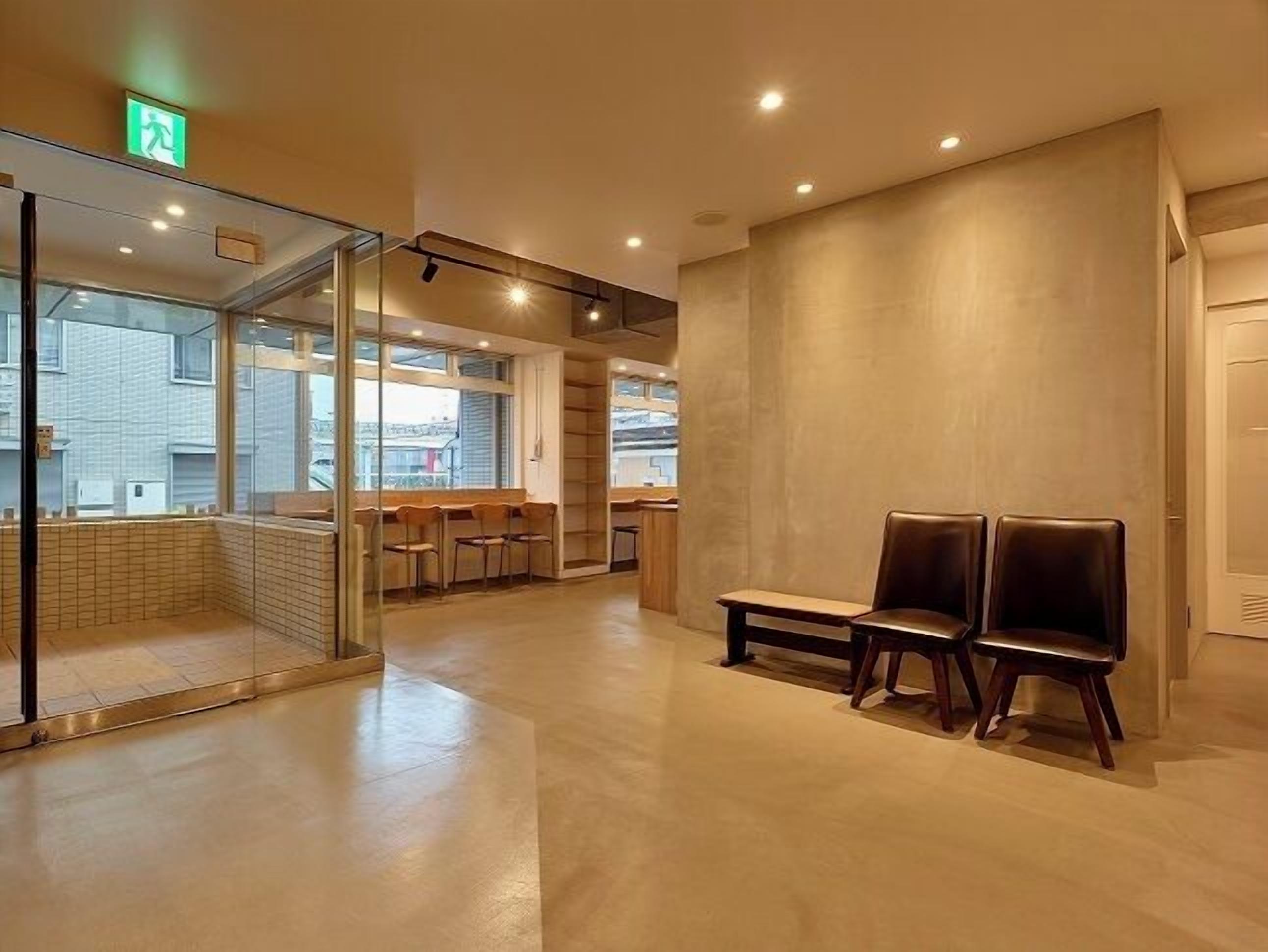 A modern waiting area with glass partitions, wooden chairs, and a bench.