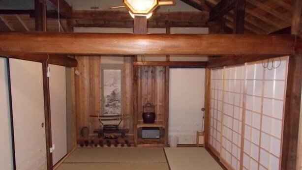 Una habitación japonesa tradicional con suelo de tatami, puertas correderas de madera y una lámpara colgante.