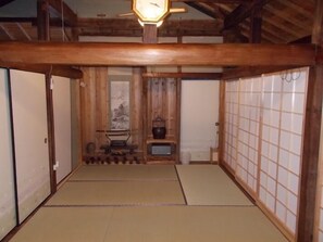 Una habitación japonesa tradicional con suelo de tatami, puertas correderas de madera y una lámpara colgante.