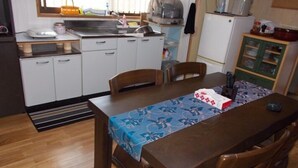 Una cocina compacta con zona de comedor, que incluye una mesa con mantel floreado, sillas de madera y un refrigerador.