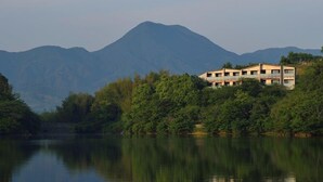 A building with multiple floors, surrounded by dense greenery and a mountain in the background. - Tobe Auberge Resort (Tobe)