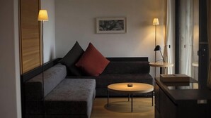 Una sala moderna con un sofá modular, una mesa de centro redonda y dos lámparas de pie.