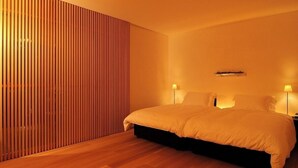A modern bedroom with a large bed, wooden slat wall, and two bedside lamps. - Tobe Auberge Resort (Tobe)