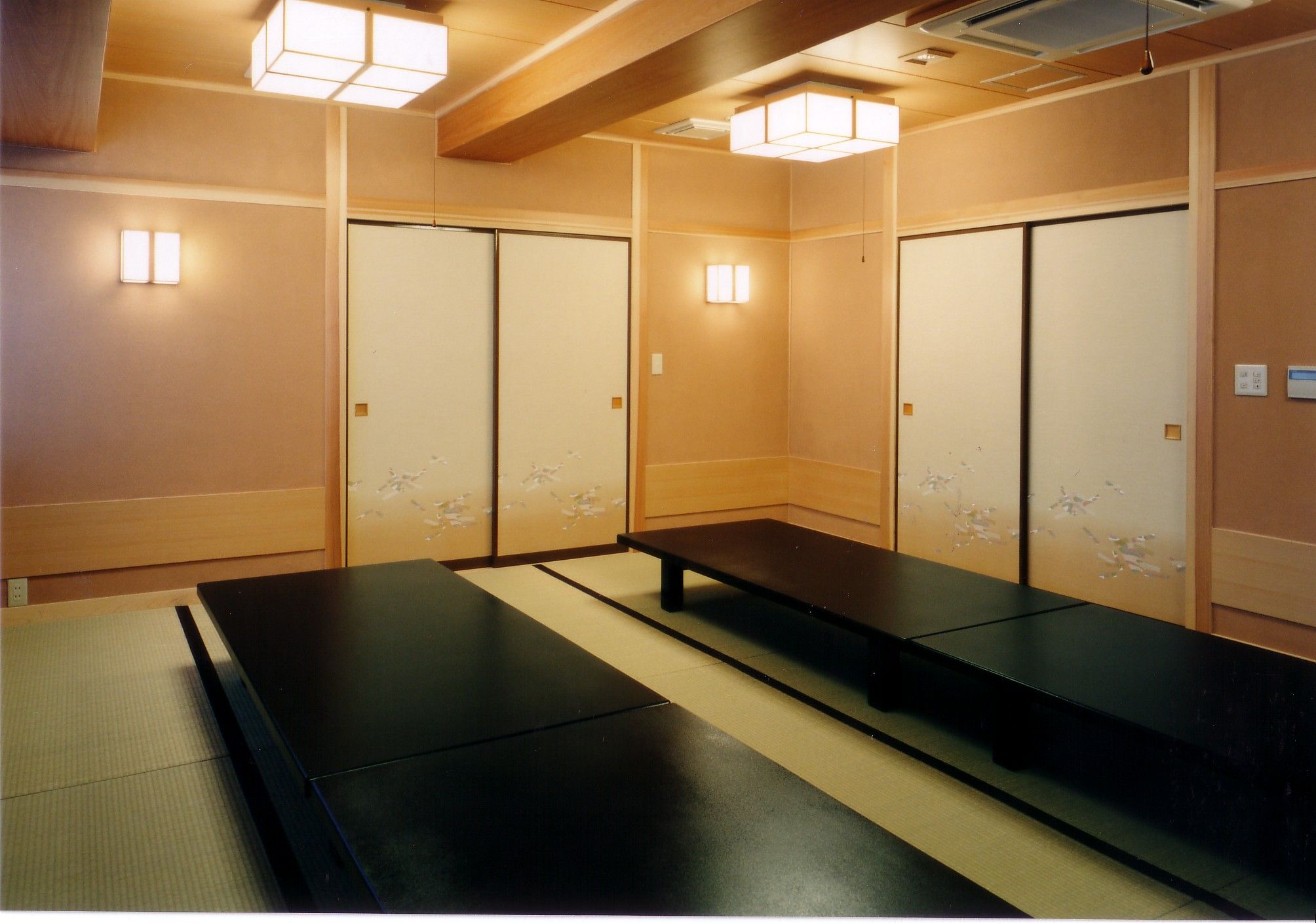 Une pièce avec des tatamis, une table basse et des portes coulissantes.