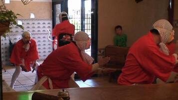 Un grupo de personas vestidas de rojo sentadas alrededor de una mesa en una habitación con piso de baldosas y pared decorada.