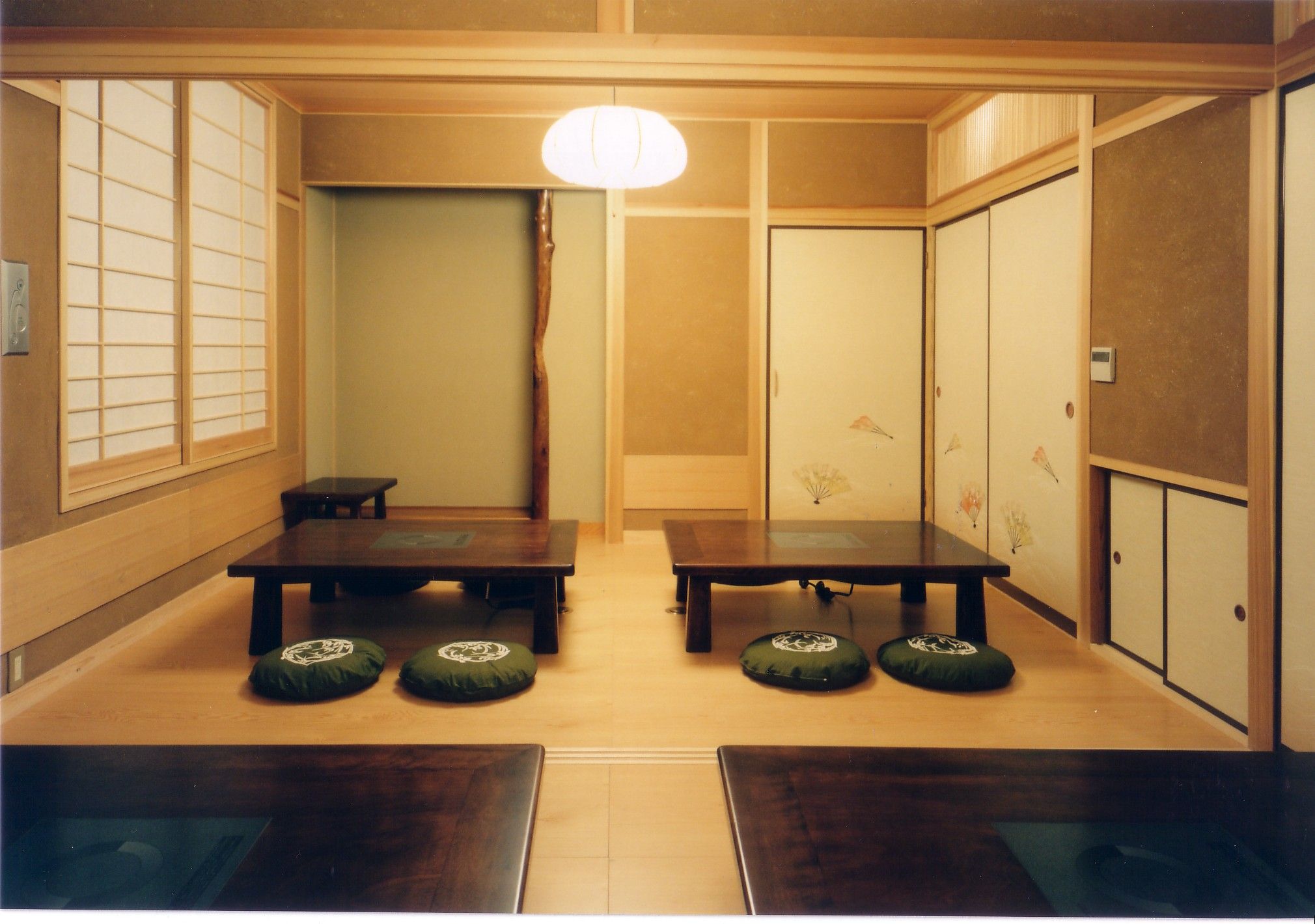Ein traditioneller japanischer Raum mit Tatami-Böden, einem niedrigen Tisch und verschiebbaren Türen.