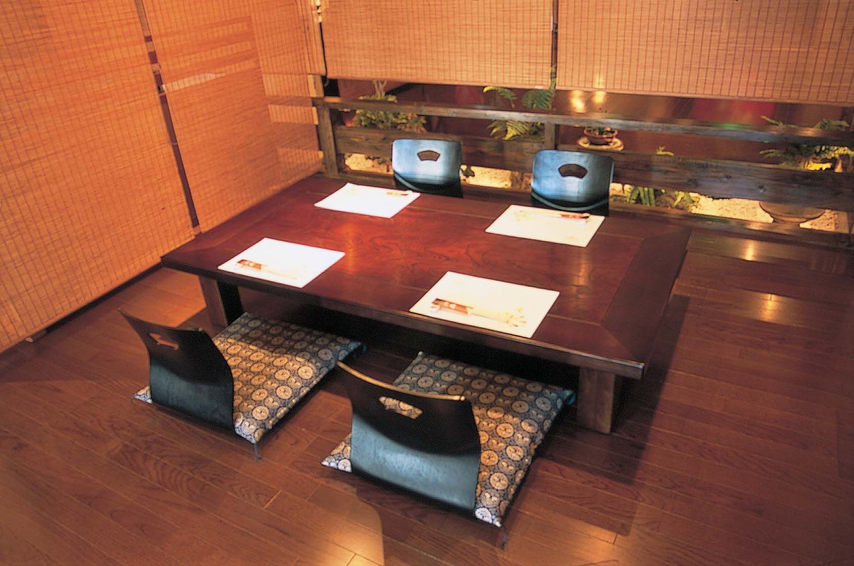 Una mesa de madera para comer con cuatro sillas, cada una con un cojín estampado.