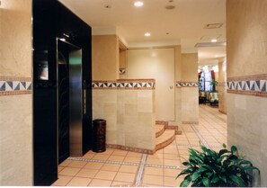 A hotel corridor with a tiled floor, a staircase, and a plant. - Hyuga Dai-ichi Hotel (Hyuga)