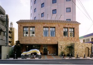 A two-story building with a stone facade, large windows, and a central entrance.