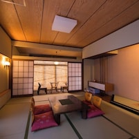 A traditional Japanese room with tatami flooring, a low table, cushions, and sliding doors.
