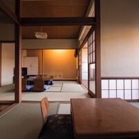 Una habitación japonesa tradicional con suelo de tatami, una mesa de madera baja y un banco acolchado.