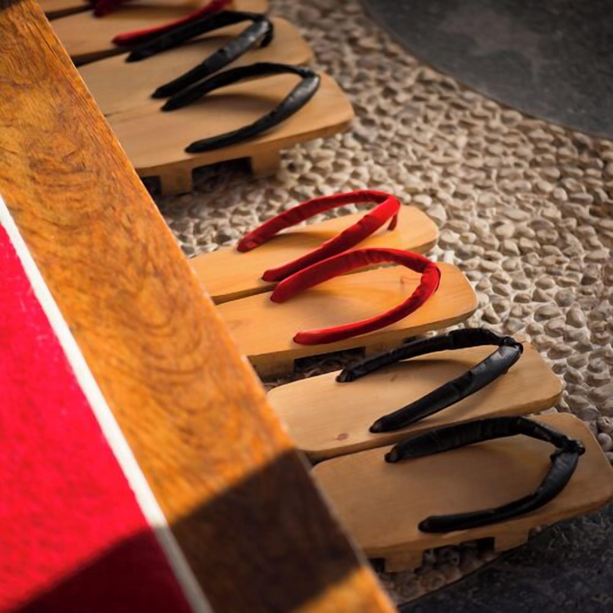 A wooden bench with red and black straps.