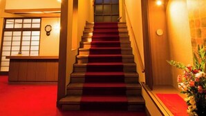 A staircase with a red carpet leading to a room with a wooden ceiling and a clock on the wall. - Yado Atagoya (Fukushima)