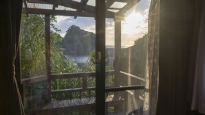Een houten balkon met uitzicht op een bergachtig landschap en een waterpartij.