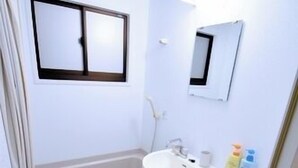 A small, compact bathroom with a toilet, sink, and window. - In The Stream (Zamami)