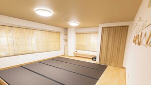 Una habitación con esteras de tatami, suelo de madera, una puerta corredera y una ventana con persianas.