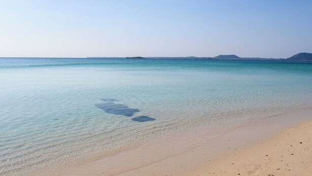 Una playa con agua turquesa cristalina y una orilla arenosa.