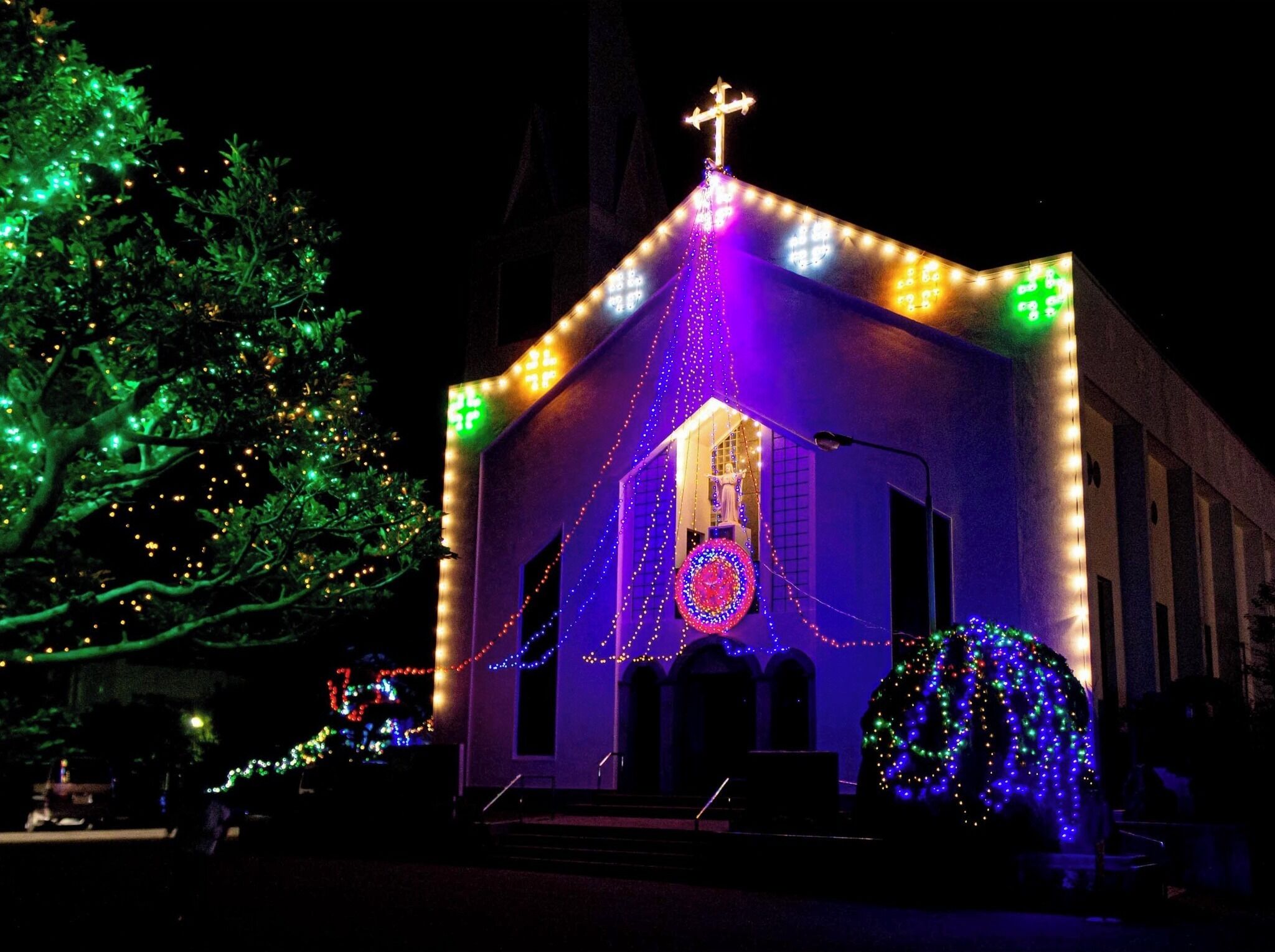 A building with a cross on top, surrounded by colorful lights.
