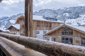 Eine Holzhütte mit großen Fenstern und einem Balkon, vor einer verschneiten Berglandschaft.