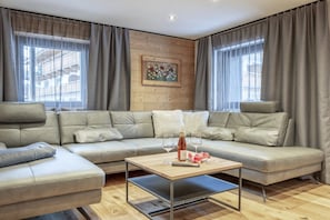 Ein modernes Wohnzimmer mit einem Ecksofa, einem Holztisch und einem Gemälde an der Wand.