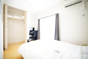 Une chambre d’hôtel équipée d’un lit, d’un bureau avec un ordinateur, d’une armoire et d’un appareil de climatisation.