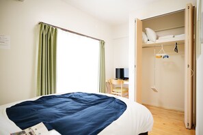 A bedroom with a bed, a desk with a computer, a wardrobe, and a hanging toy rack. - Condominium Golf Golf Tsuboya (Naha)