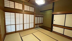 Une pièce de style japonais traditionnel, avec un sol recouvert de tatamis, des paravents en papier de riz (shoji) et un plafond en bois.