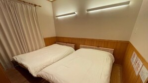 Une chambre avec deux lits, des têtes de lit en bois et un luminaire au plafond.