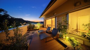 A modern outdoor patio with seating and plants, overlooking a scenic landscape. - Hotel Hamatoku (Iwaki)