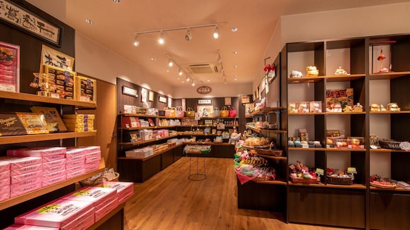 A well-lit store with wooden floors and shelves stocked with various items including boxes, bags, and decorative objects.