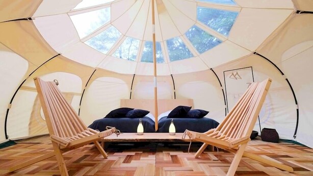 A tent with a central seating area, two wooden chairs, a sofa, and a table with two lamps. - Rita's Ranch Minami Karuizawa (Karuizawa)