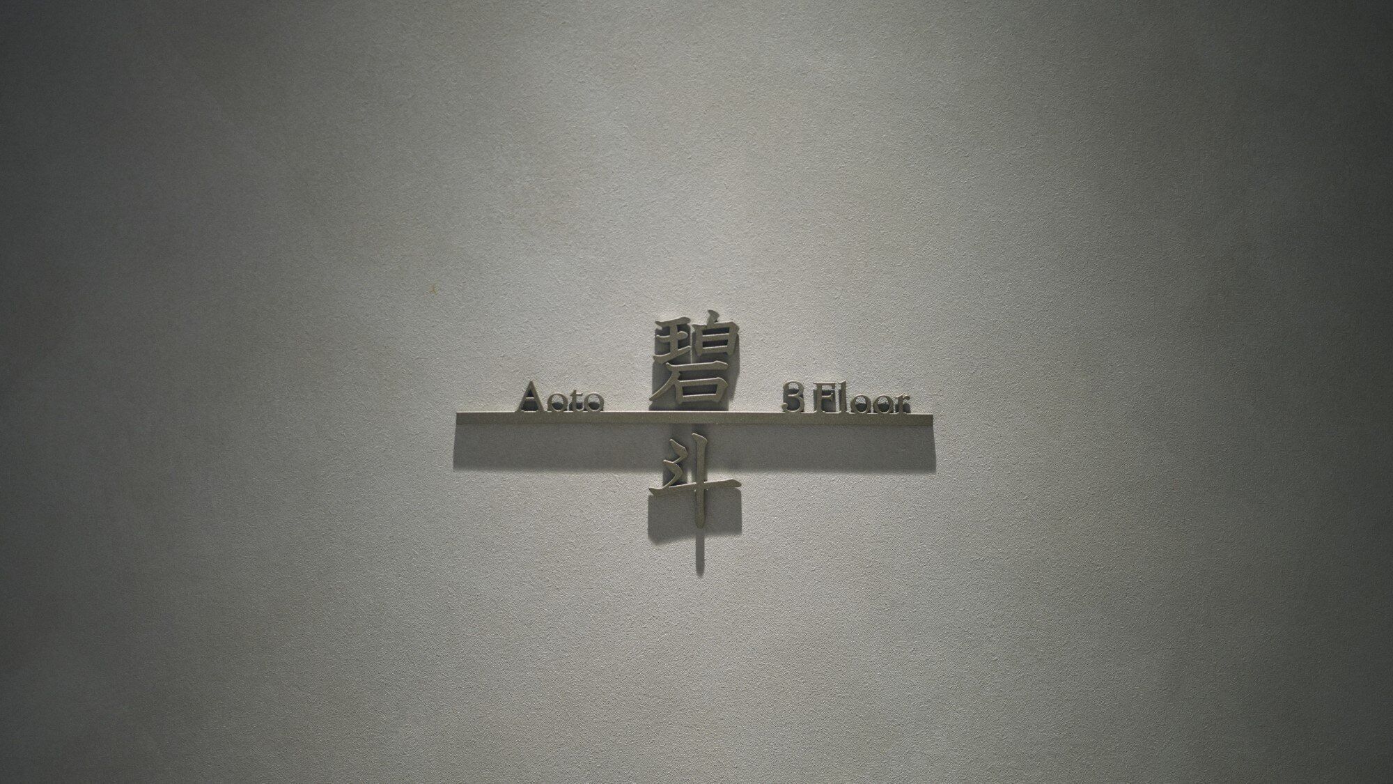Un letrero en la pared con el texto 'Ato 8 Floor' y un símbolo que indica una ubicación o dirección.