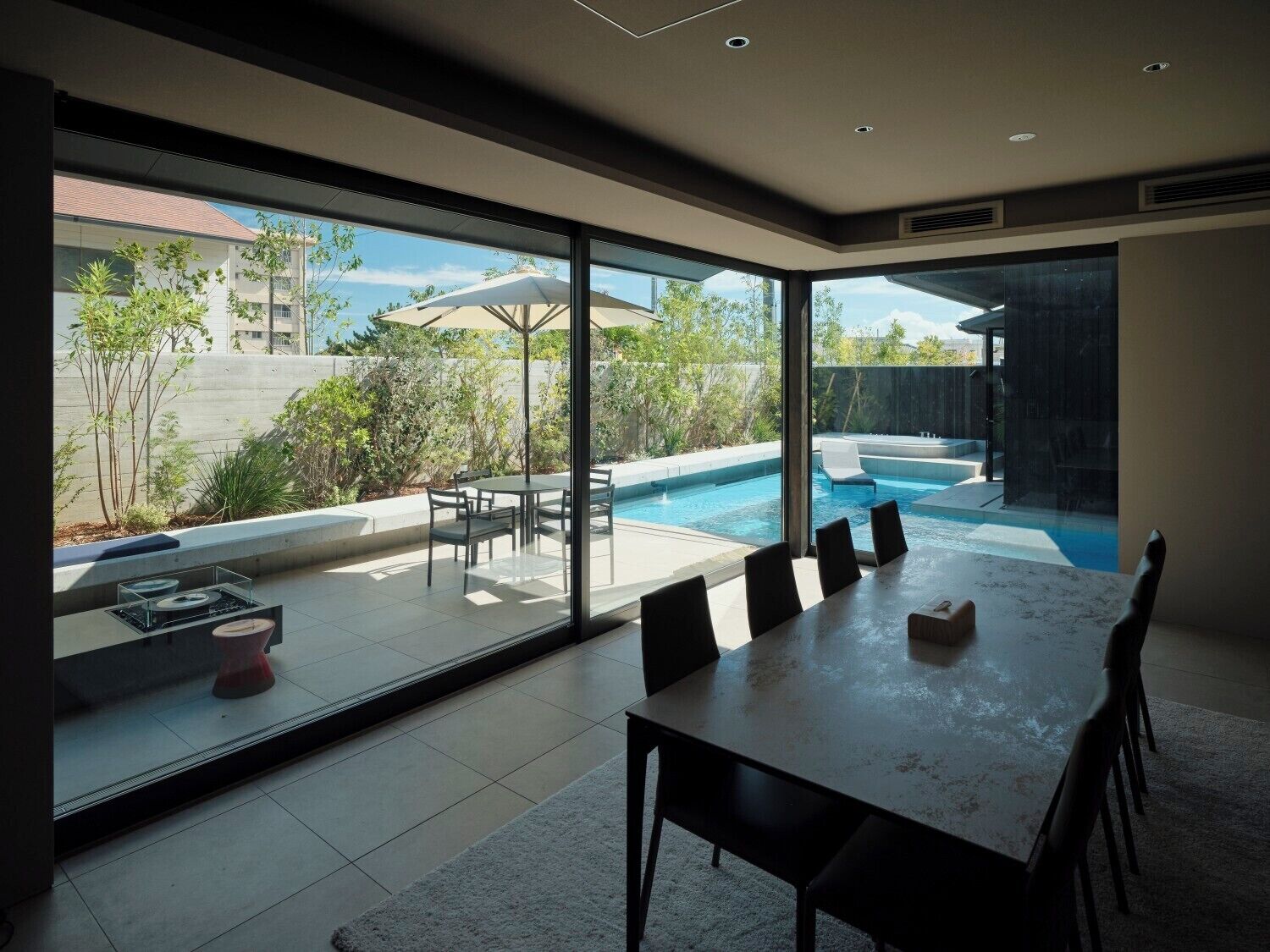 Un comedor moderno con una mesa grande y sillas, una piscina y vistas al exterior.