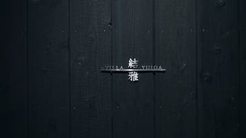 A dark wooden door with a metal plaque that reads 'VILLA YUIGA' in both English and another script.