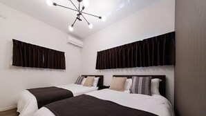 A hotel room with two beds, dark curtains, a ceiling light fixture, and an air conditioning unit. - Shipponomori Resort Awajishima Sauna & Studio (Awaji)