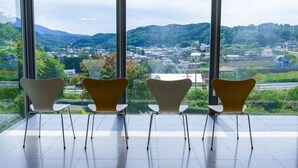 Un interior moderno con amplios ventanales que ofrecen vistas a un pueblo y colinas.