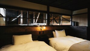 A room with two beds, a wooden headboard, a large window with a view of a staircase, and a wall-mounted light fixture. - Paak Hotel (Nichinan)