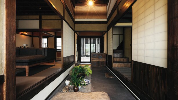 A traditional Japanese interior with tatami flooring, a low wooden table, a sofa, and a staircase. - Paak Hotel (Nichinan)