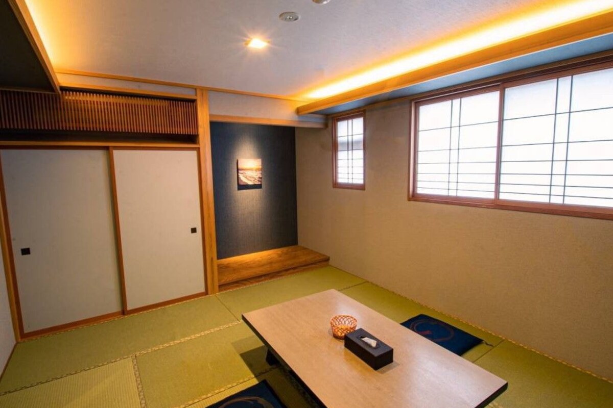 A traditional Japanese room with tatami flooring, a low table, and sliding doors.