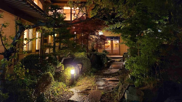 En traditionel japansk bygning om natten med en stentrappe, der fører til indgangen.