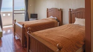 A hotel room with two wooden beds, a television, and a window with curtains. - Uminchuno Yado (Nago)