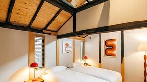 A bedroom with a wooden ceiling, a bed with white bedding, two bedside tables with lamps, and artwork on the walls. - Yado Charinko (Gose)