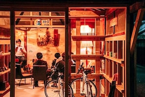 A cozy, rustic interior with wooden shelves and a bicycle in the foreground. - Yado Charinko (Gose)
